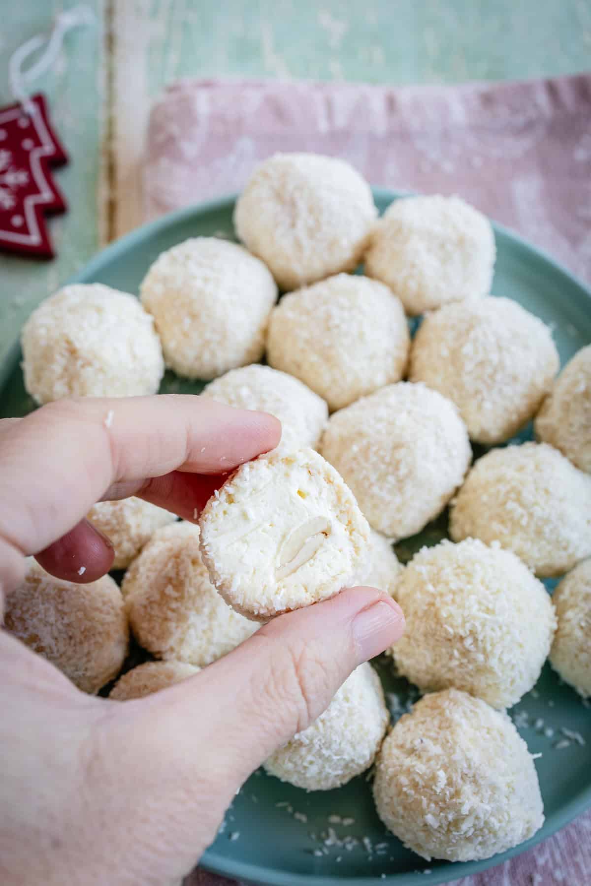 a woman holding a sliced Raffaello ball on top of many