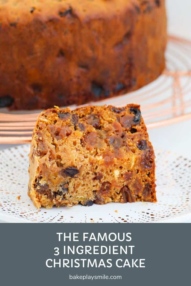 A piece of Christmas fruit cake on a plate, with the rest of the cake b=in the background