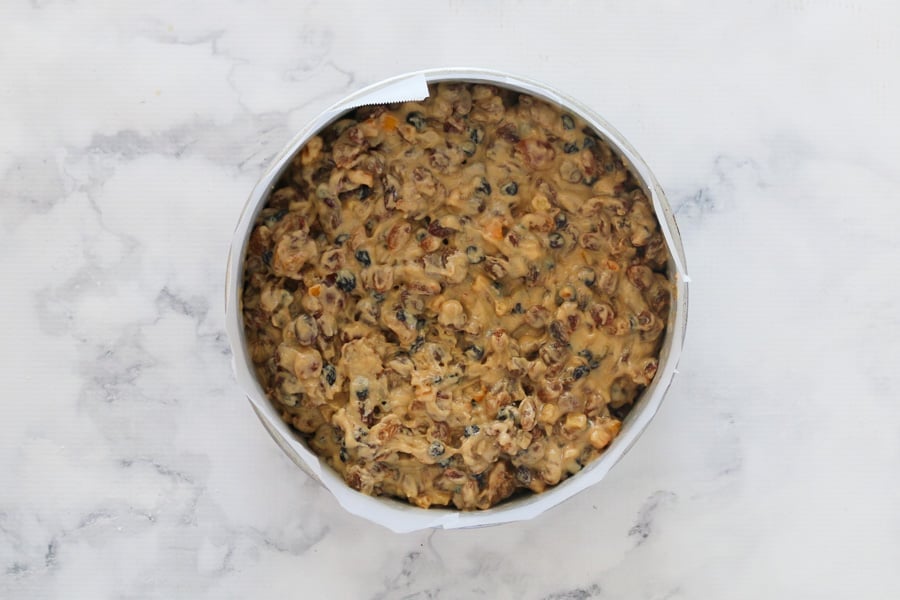 An overhead shot of an uncooked fruit cake in a baking tin.