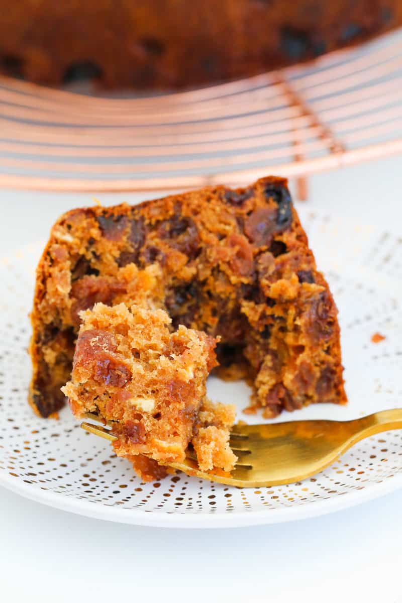 A gold fork with a piece of Christmas cake on it on a plate.