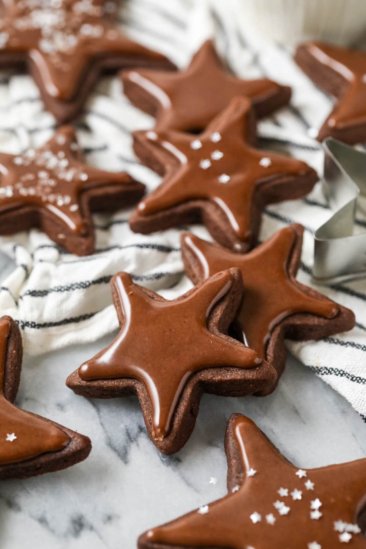 Chocolate star sugar cookies topped with chocolate frosting and silver stars.