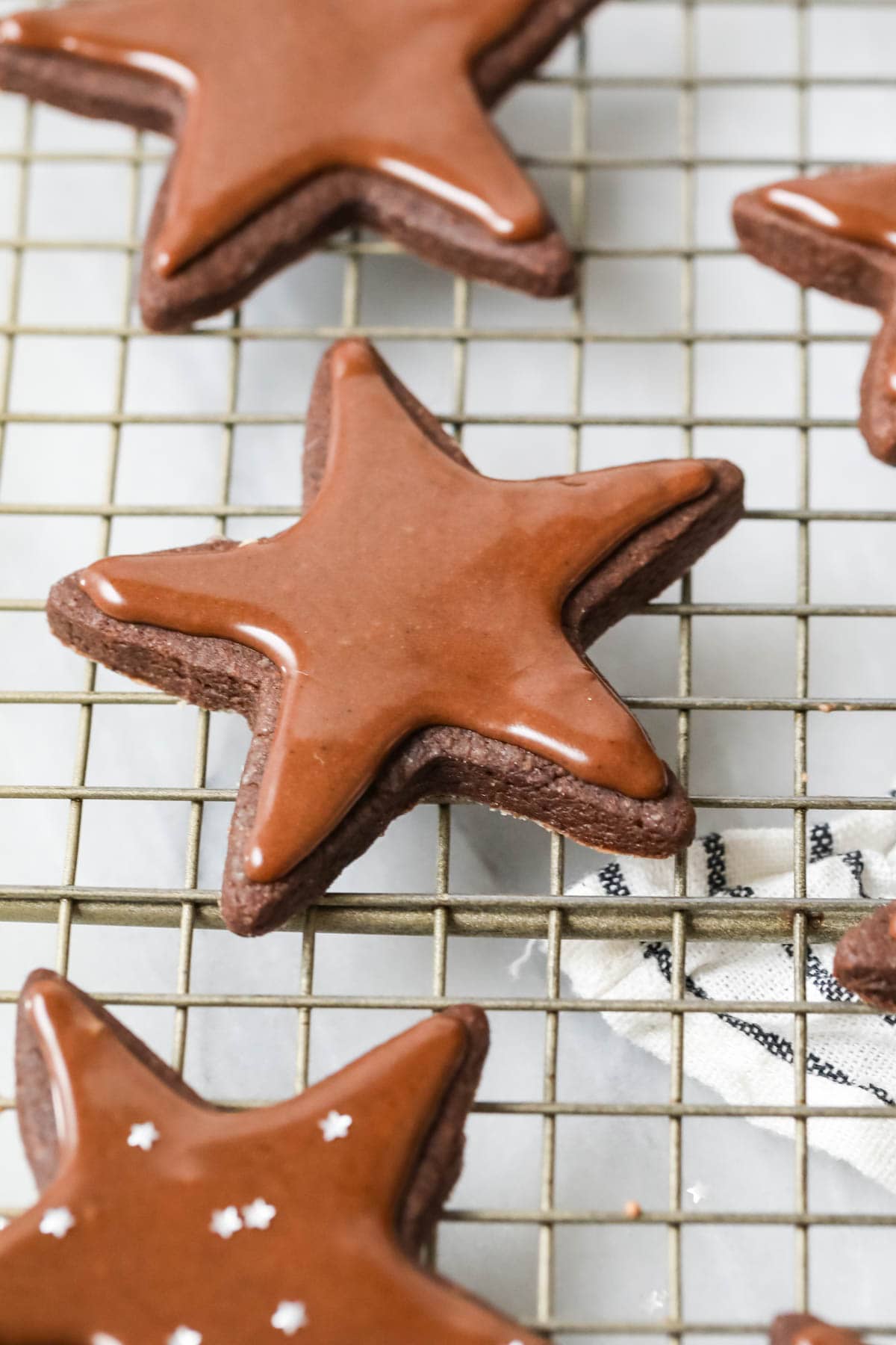 Close-up view of a chocolate sugar cookie that's been cut into a star shape and topped with shiny chocolate icing.