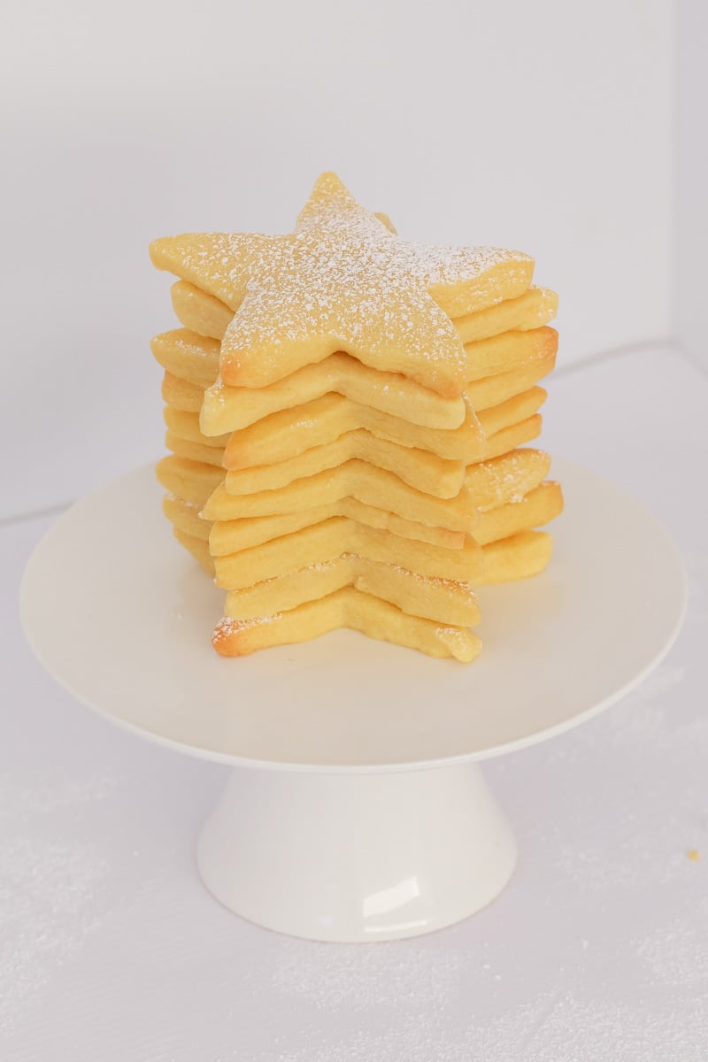 A stack of star shaped Christmas shortbread cookies dusted with icing sugar. 