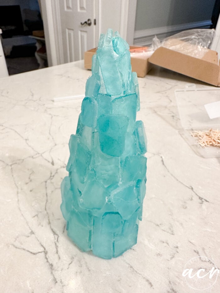the tree standing up covered completely with sea glass