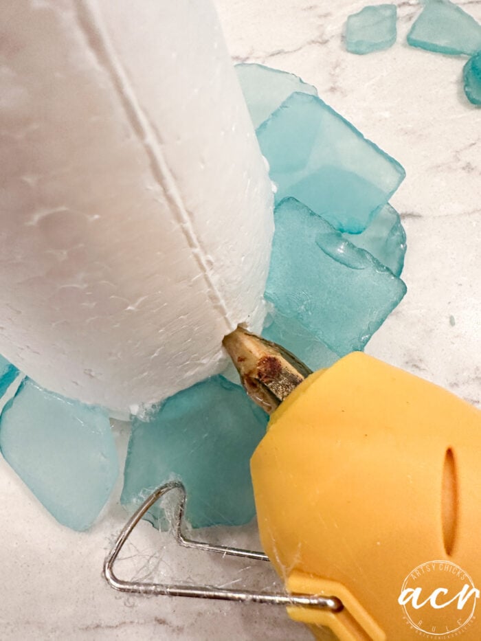 adding glue with glue gun to hole made for glass to fit in