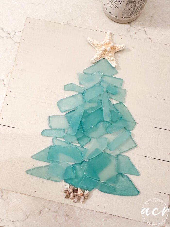 seashells and sea glass lid out into a tree shape on board/sign
