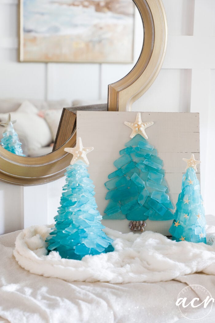 3 aqua christmas trees on white fluffy fabric with mirror behind