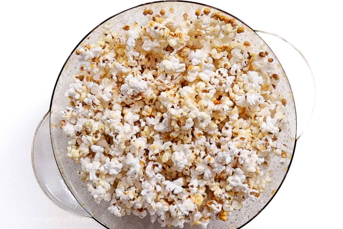 A bowl filled with freshly popped kettle corn, perfectly coated with a light layer of sugar and oil, showing a golden and crispy texture ready for snacking.