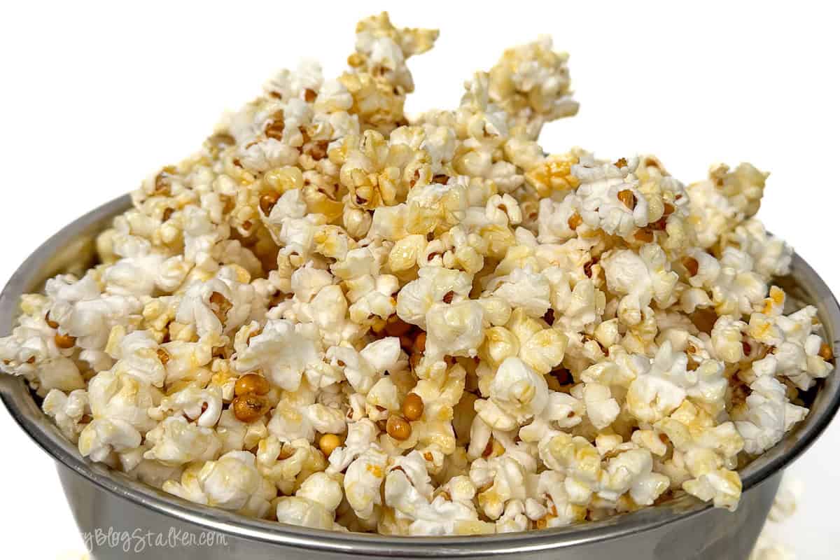 A close-up of a silver bowl filled with golden, crispy kettle corn, showcasing its perfect sweet and salty coating, ready to be enjoyed as a tasty snack.