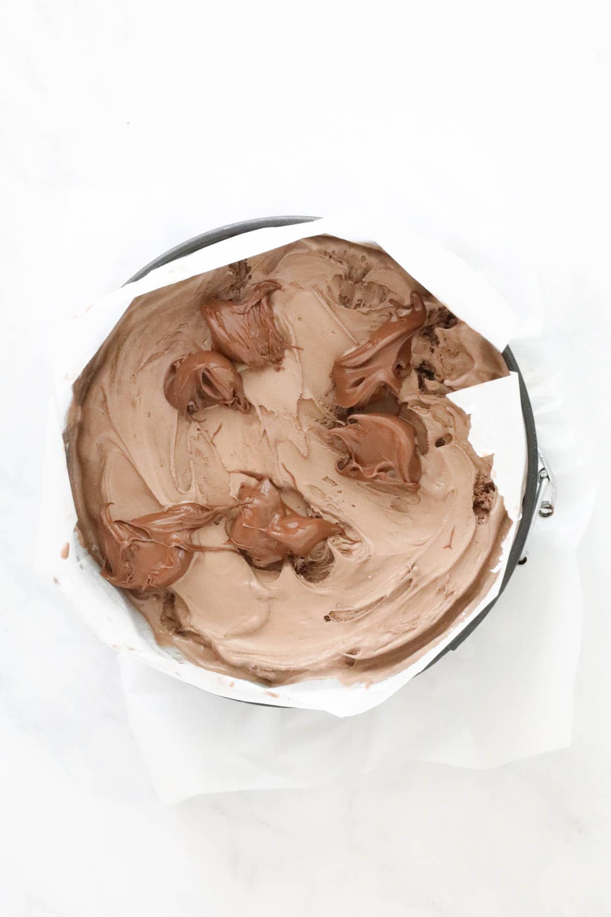 Chocolate ice cream spread over the Oreo base, and spoonfuls of Nutella dotted over the top.