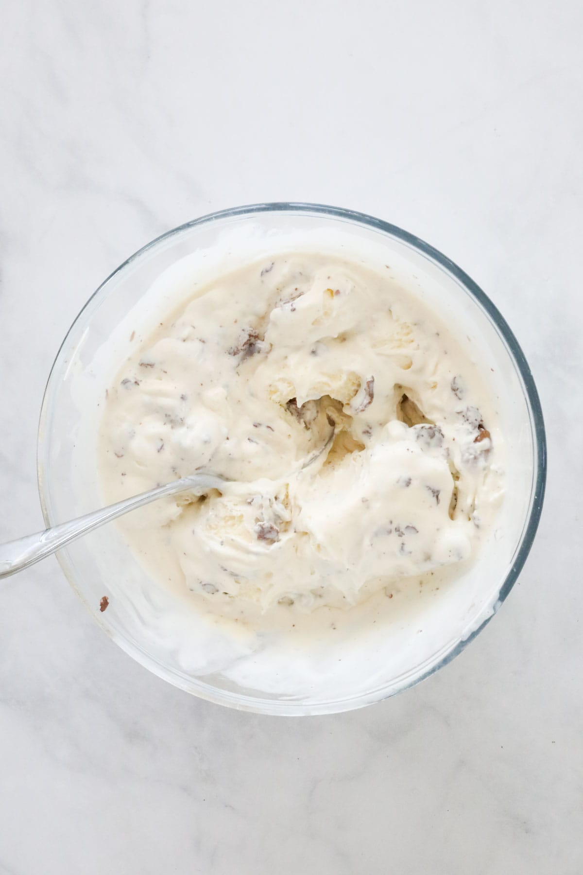 Vanilla ice cream and chopped Ferrero Rocher mixed together in a bowl.