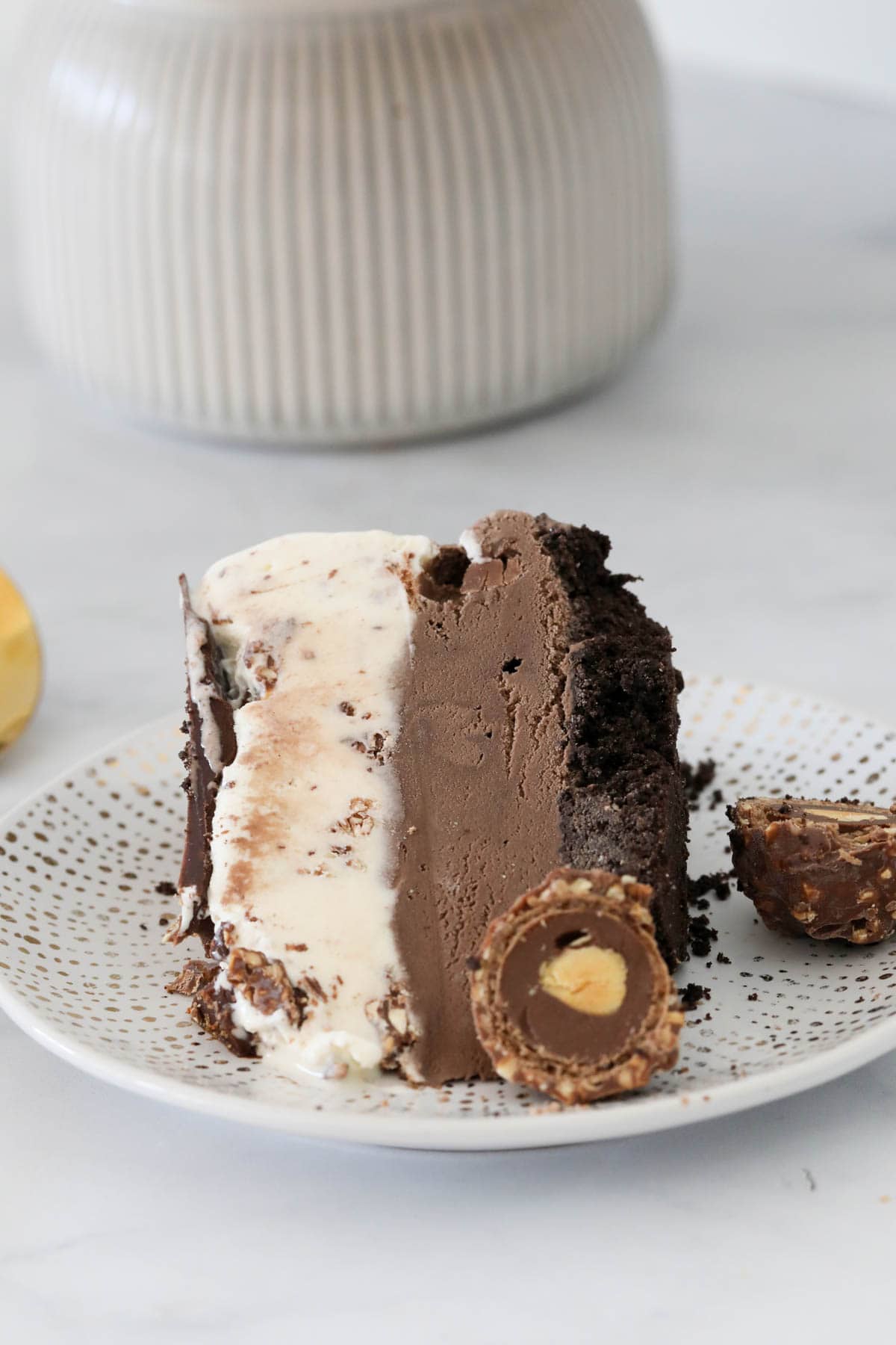 A slice of layered Ferrero Rocher ice cream cake on a plate.