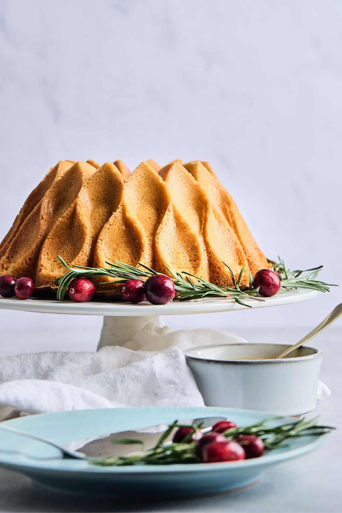A side view of an eggnog pound cake on a white cake stand.