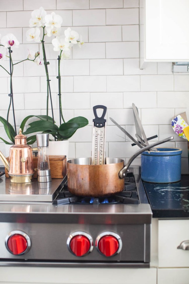 A saucepan on a stove with a candy thermometer.