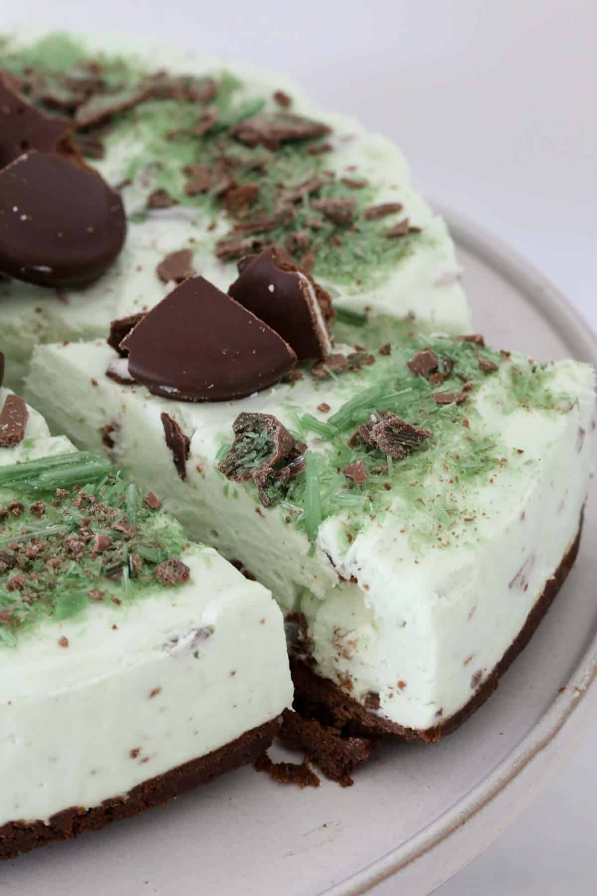 Peppermint cheesecake on a plate with a slice cut out of the cheesecake.