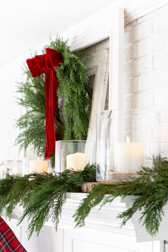 White Christmas mantel decorated for Christmas using a classic red and green holiday color scheme.