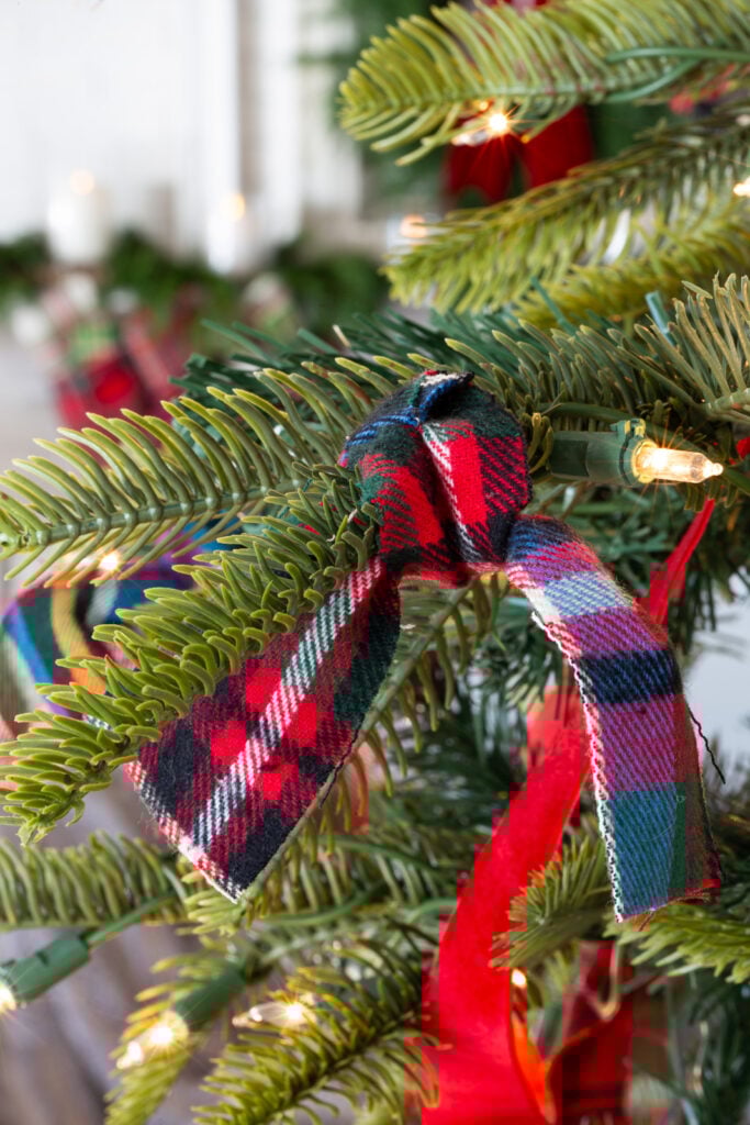 Red plaid flannel fabric strip tied onto a Christmas tree branch.