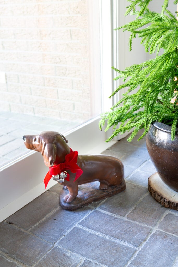 Dog statue with a red bow and jingle bells around his neck.