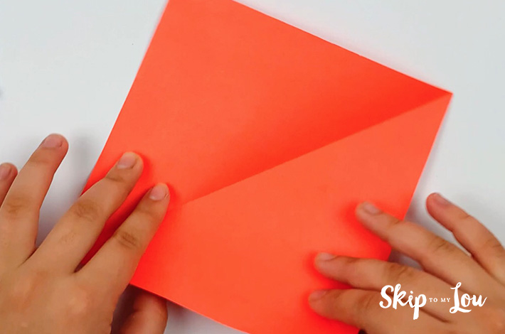 Two hands unfolding the paper and turning it.