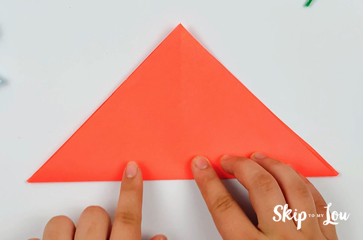 Two hands folding the second triangle.