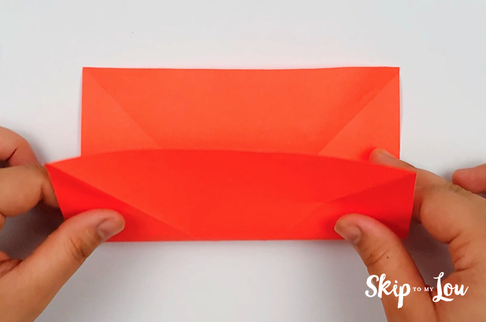 Two hands folding the bottom flap towards the top flap.