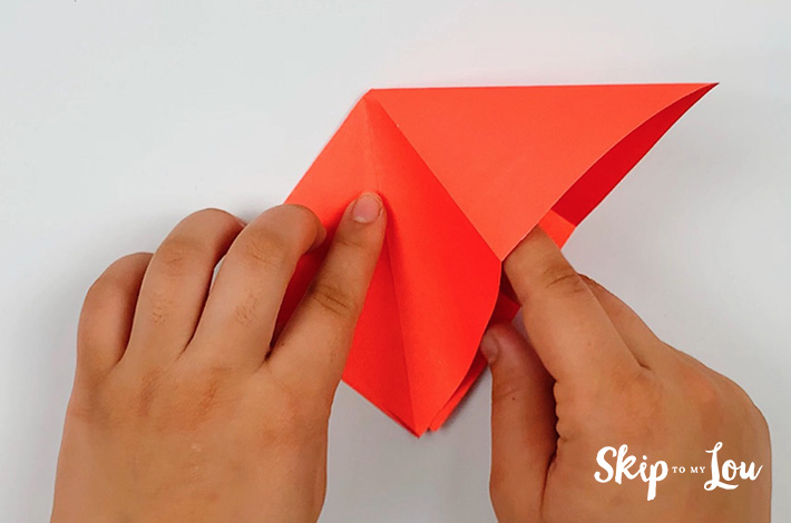 Two hands making the same fold on the left as was done on the right.