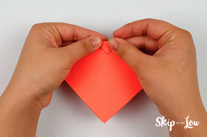 Two hand folding the top triangle of the kite shape foward.