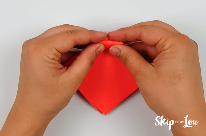 Two hand folding the top triangle of the kite shape backward.