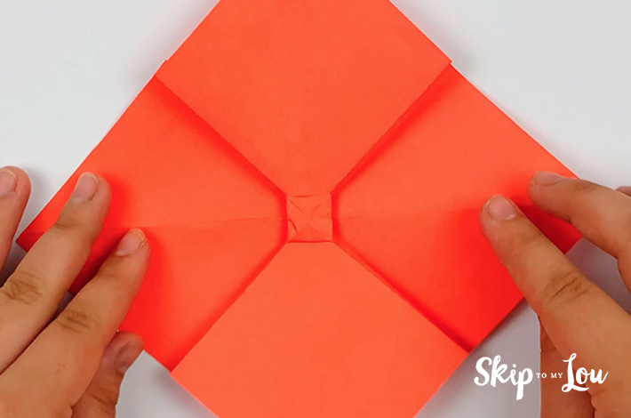 Two hands unfolding the paper.
