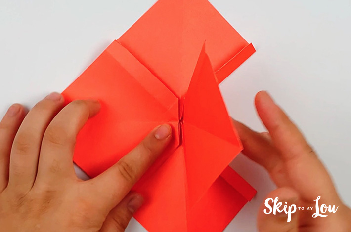 Two hands folding the left flap over.