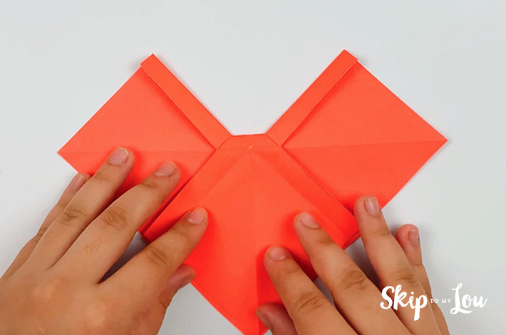 Two hands turning the paper 90 degrees.
