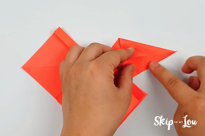Two hands folding the top section and bottom section of the right flap.
