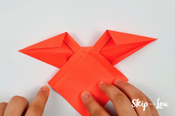 Two hands folding the top section and bottom section of the left flap.