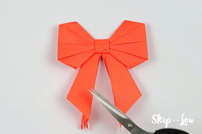 Two hands trimming the ends of the ribbon with a scissors.