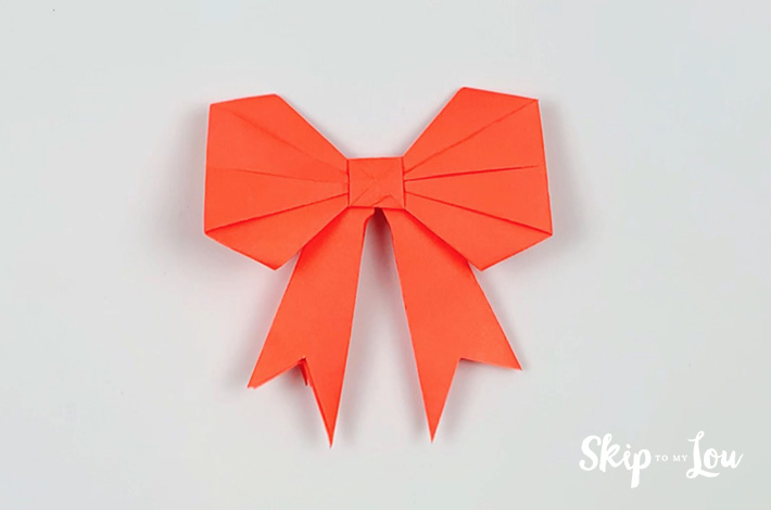 Two hands cutting a V-shape at the end of the ribbon.
