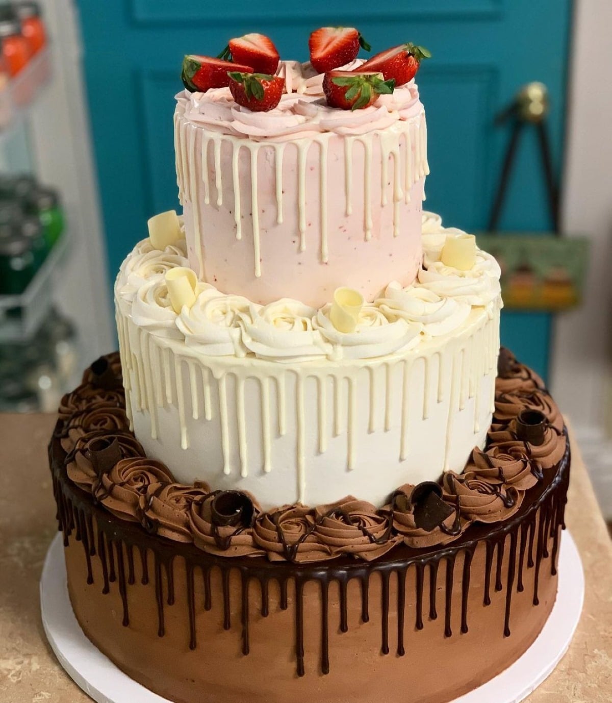 three tiered neapolitan wedding cake with a chocolate bake, vanilla center, and strawberry cake on top.