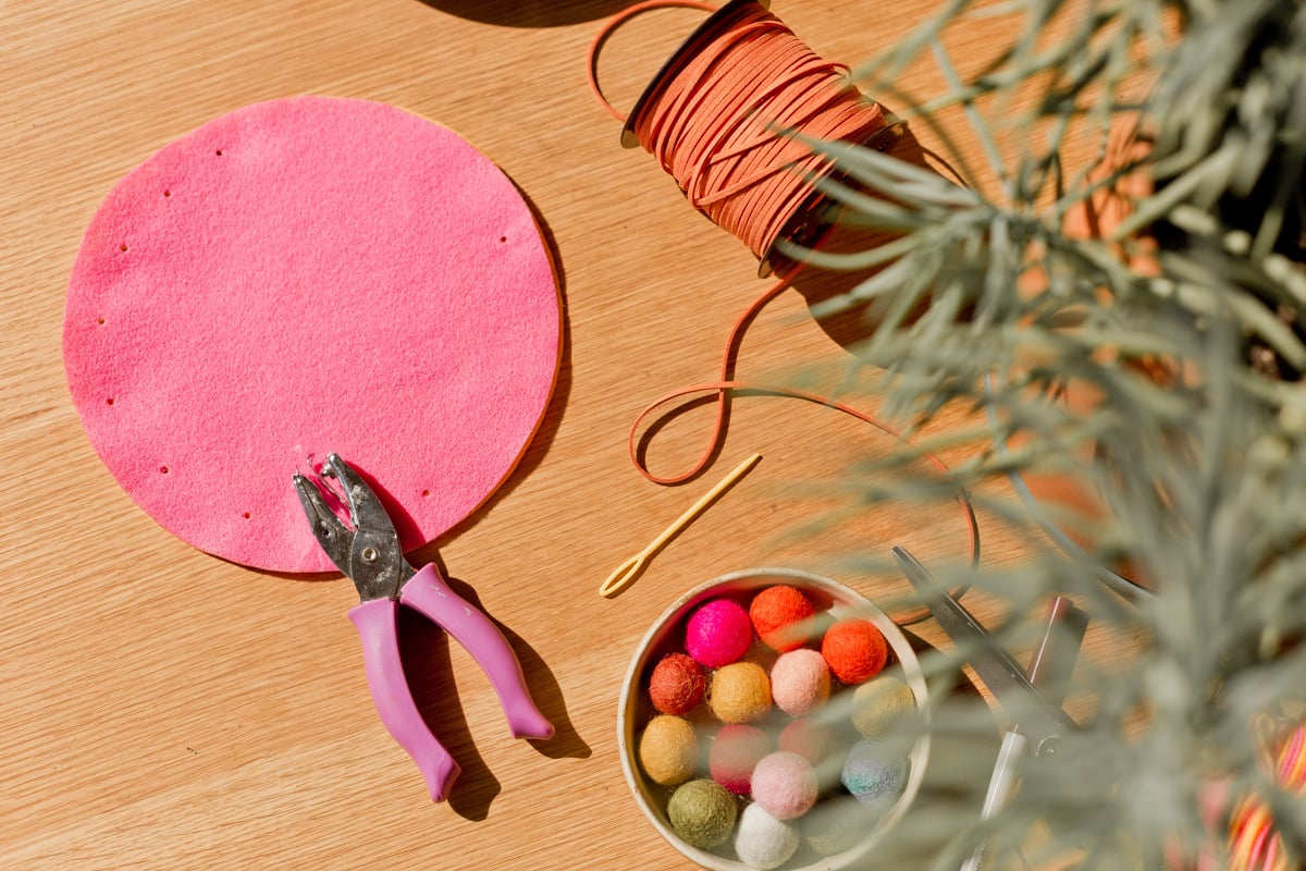 punching holes into circular pieces of felt to create a diy pouch
