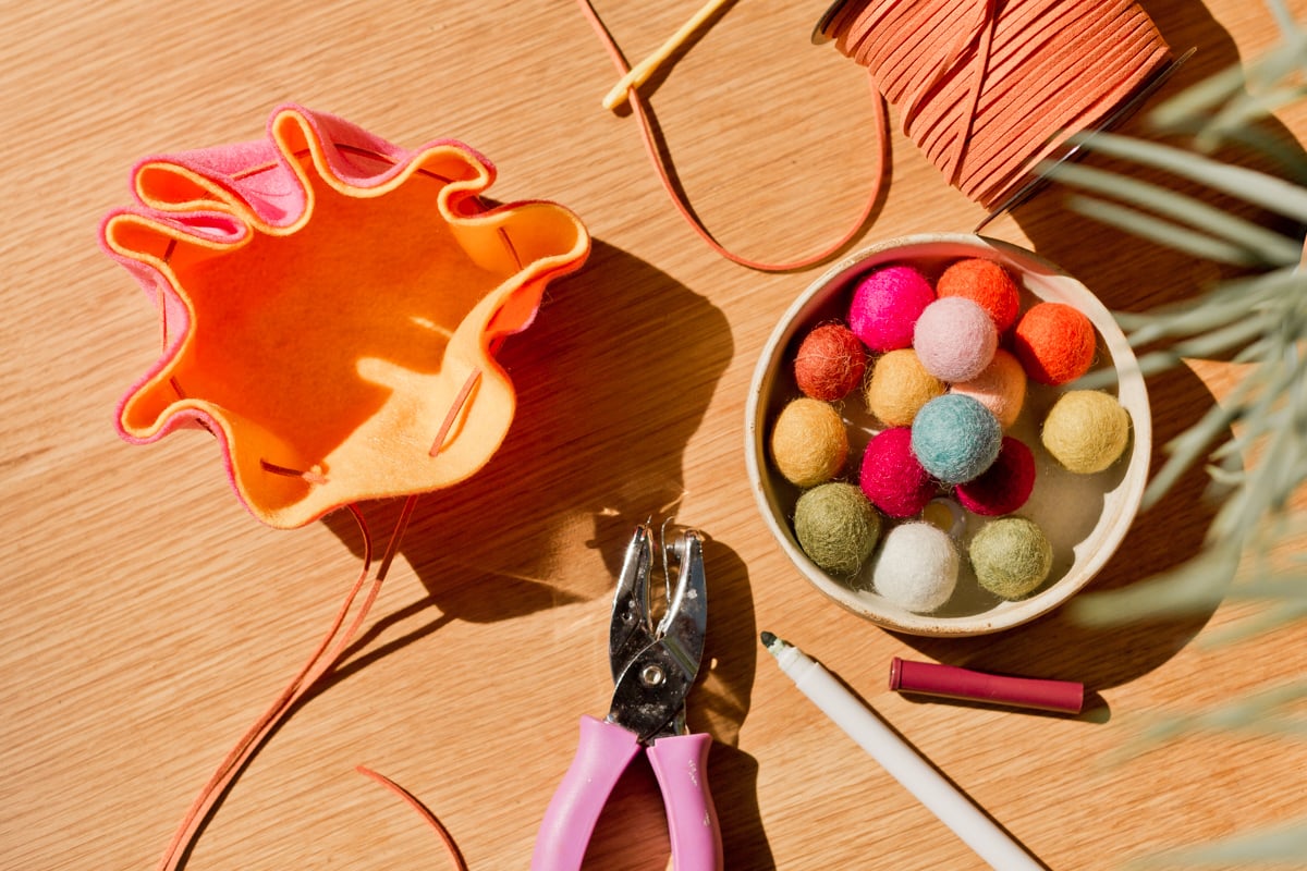 felt pouch being made, with a hole punch and felt balls