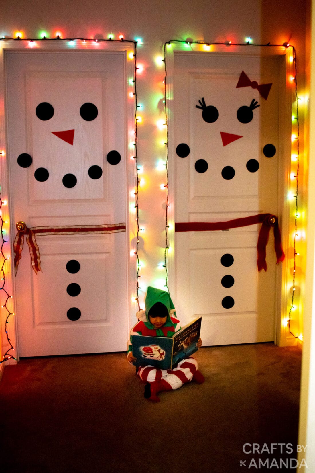 child reading book with snowman decorated doors in background