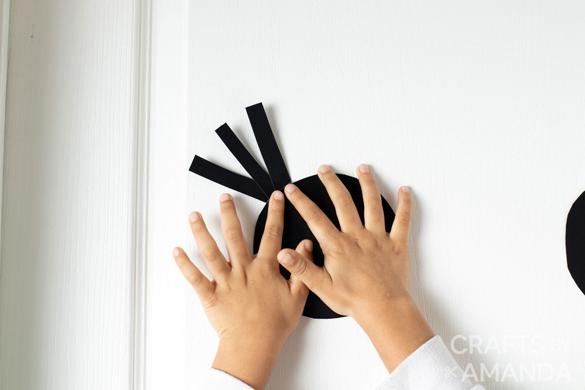 child attaching card stock pieces to door