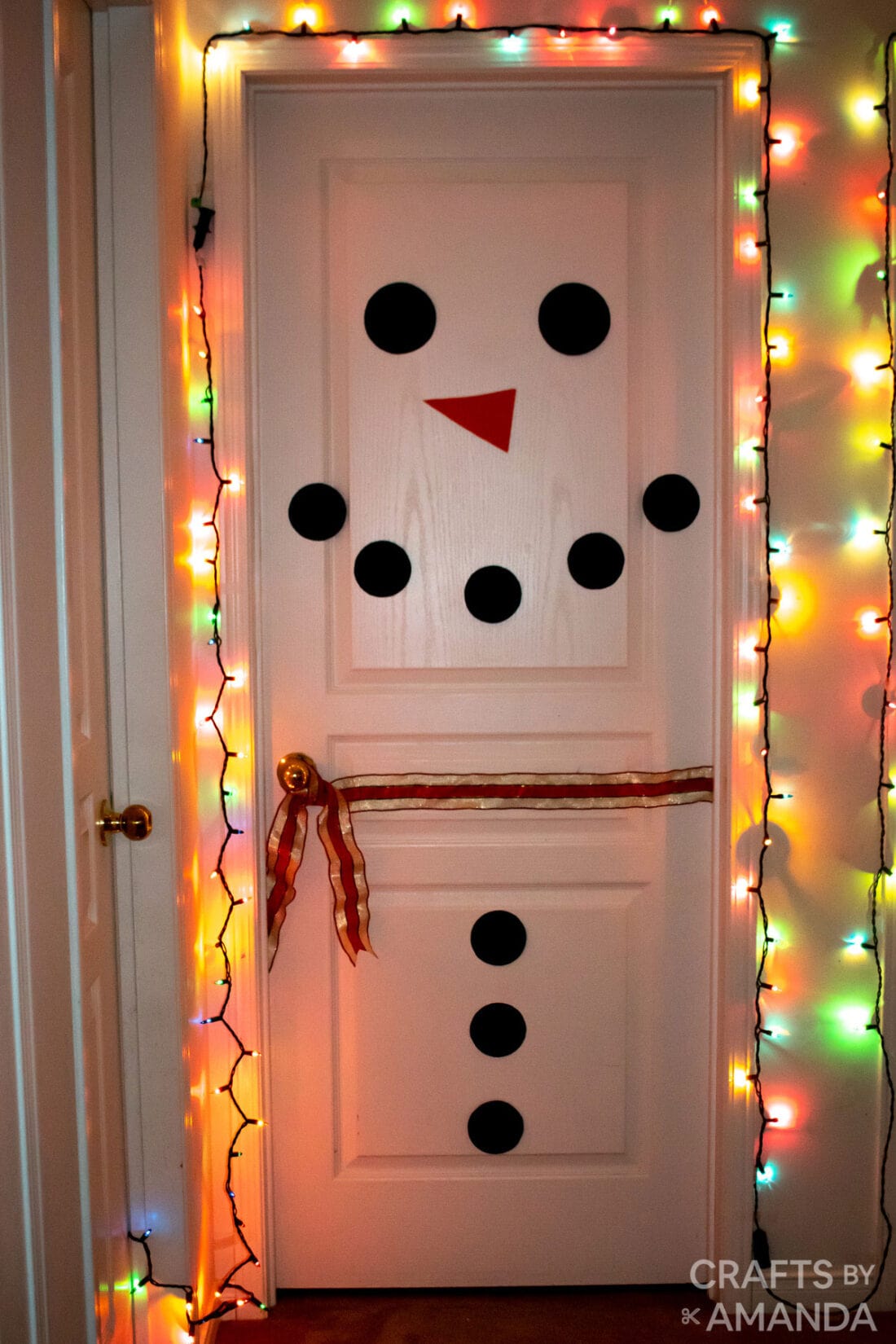 snowman decorated door with christmas lights around it