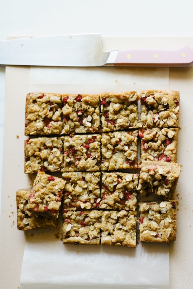 Rhubarb blondies on a cutting board with a pink chef's knife