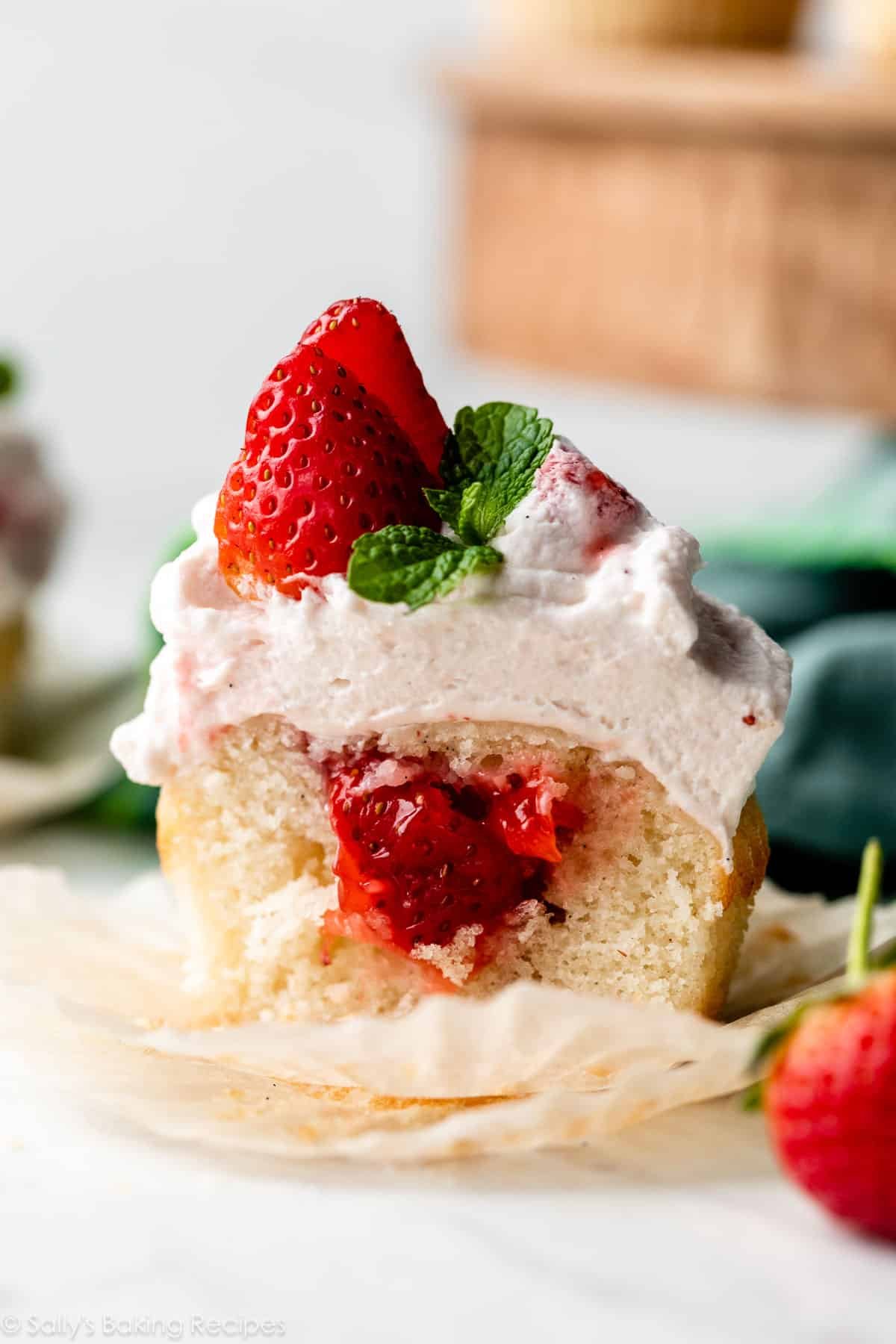 close-up of strawberry shortcake cupcake cut in half to show strawberry filling.